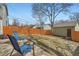 Inviting backyard with mature trees, wooden fence, concrete patio, and seating area with fire pit at 2650 Perry St, Denver, CO 80212