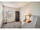 Cozy bedroom featuring soft carpeting, a tall dark wood armoire, and a patterned accent chair with a lamp at 2650 Perry St, Denver, CO 80212