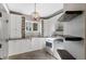 Laundry room boasts white shaker cabinets, a farmhouse sink, and rustic wood shelves at 7181 Longview Dr, Niwot, CO 80503