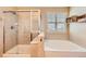 Bright bathroom featuring a glass-enclosed shower, large tub, and neutral tile throughout at 6892 Turnstone Ave, Castle Rock, CO 80104