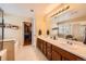 Bright bathroom featuring double vanity, large mirror, and walk-in closet with an organized storage system at 6892 Turnstone Ave, Castle Rock, CO 80104