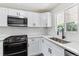 The renovated kitchen features stainless appliances, white cabinetry, and quartz countertops at 1032 Geneva, Aurora, CO 80010