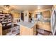 Spacious kitchen featuring a granite island, wooden cabinets, a view of the staircase, and modern appliances at 13661 W Tufts Ave, Morrison, CO 80465