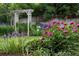 Lush backyard featuring vibrant flower gardens, a wooden fence, and an attractive pergola, perfect for outdoor enjoyment at 7189 S Kline St, Littleton, CO 80127