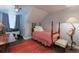 Cozy bedroom featuring a sloped ceiling, window, and a four poster bed with red and white checked bedding at 7189 S Kline St, Littleton, CO 80127