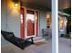 Cozy front porch with a charming swing, red front door, and detailed brickwork, providing a welcoming entrance at 7189 S Kline St, Littleton, CO 80127