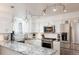 Modern kitchen featuring granite countertops, stainless steel appliances, white cabinets, and contemporary lighting fixtures at 7189 S Kline St, Littleton, CO 80127