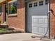 Close-up of garage door with electric car charging station, attached to a brick house at 6314 Brooks Dr, Arvada, CO 80004