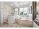 Luxurious bathroom featuring a large soaking tub, tiled shower, and natural light at 13962 W 76Th Ln, Arvada, CO 80005