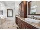 Bathroom with dual sinks, dark cabinets, granite countertops, and ornate mirrors at 13962 W 76Th Ln, Arvada, CO 80005