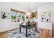 Cozy dining room with a view of the backyard, featuring hardwood floors and a modern chandelier at 13962 W 76Th Ln, Arvada, CO 80005