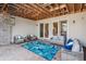 Covered patio area with string lights, stylish seating, and stone accent wall at 13962 W 76Th Ln, Arvada, CO 80005