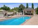 A large in-ground pool with surrounding concrete decking, poolside furniture, and a pool house at 13962 W 76Th Ln, Arvada, CO 80005