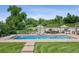 An in-ground pool with an automatic cover, surrounding concrete decking, and poolside furniture on a grassy lot at 13962 W 76Th Ln, Arvada, CO 80005