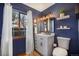 Stylish bathroom featuring blue walls, a white vanity, a modern mirror, and natural light from the window at 10873 W 84Th Pl, Arvada, CO 80005