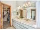 Bathroom featuring a double sink vanity with a walk-in closet filled with hanging clothes in the background at 10873 W 84Th Pl, Arvada, CO 80005