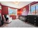 Bedroom featuring a crib, changing table, and comfortable chair in a room with maroon walls at 10873 W 84Th Pl, Arvada, CO 80005