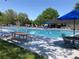 Community pool with blue lounge chairs, picnic tables, and umbrellas on a sunny day at 10873 W 84Th Pl, Arvada, CO 80005