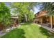 A spacious backyard featuring lush green grass, mature trees, and a cozy covered patio area at 10886 E Crestline Cir, Englewood, CO 80111