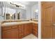 Bathroom with double sinks, wooden cabinets, tiled backsplash and decorative lighting at 10886 E Crestline Cir, Englewood, CO 80111