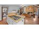 Open concept living space featuring a kitchen island with gas stove, hardwood floors, brick fireplace, and wood-paneled walls at 10886 E Crestline Cir, Englewood, CO 80111