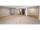 Open basement area with gray carpet, neutral walls, white support columns, and multiple doorways at 3685 Roberts St, Mead, CO 80542