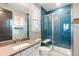 Modern bathroom features stylish blue tile, glass enclosed shower, floating vanity with stone countertop, and ample light at 26 Damsire Dr, Littleton, CO 80123