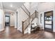 Inviting foyer featuring wood floors, staircase with black metal railings, and modern decor at 26 Damsire Dr, Littleton, CO 80123