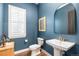 Charming powder room with blue walls, white fixtures, framed art, and natural light at 26 Damsire Dr, Littleton, CO 80123