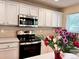 Well-lit kitchen featuring stainless steel microwave, white cabinets, and tiled backsplash at 4788 Laurelglen Ln, Highlands Ranch, CO 80130