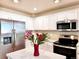 Modern kitchen with stainless steel appliances, white cabinets, and an island with a red vase of flowers at 4788 Laurelglen Ln, Highlands Ranch, CO 80130