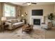 Stylishly staged living room with neutral decor, a cozy fireplace, and a large window for natural light at 4788 Laurelglen Ln, Highlands Ranch, CO 80130