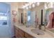 Bright bathroom featuring dual sinks, wood cabinets, large mirrors, and neutral countertops at 7053 S Shawnee St, Aurora, CO 80016