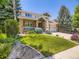 Beautifully landscaped front yard with mature trees surrounding a charming two-story home at 7053 S Shawnee St, Aurora, CO 80016