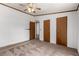 Carpeted bedroom featuring three wood-toned doors, and a ceiling fan at 205 Spruce Ave, Lochbuie, CO 80603