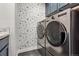 Modern laundry room with stainless steel washer and dryer set and floral wallpaper at 2934 Braeburn Way, Highlands Ranch, CO 80126