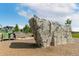 A rock climbing structure in a park offers a fun, active outdoor experience with a playground in the background at 5880 Beeler Ct, Denver, CO 80238