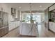 Modern white kitchen with a central waterfall island, stainless steel appliances, and an open living area at 5880 Beeler Ct, Denver, CO 80238