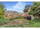 View of a yard with a weathered deck, weeds, trash bins, and the back of the house at 2421 N York St, Denver, CO 80205