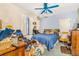 Bedroom featuring a blue ceiling fan, blue walls, bed with blue comforter, and cluttered desk and floor at 2421 N York St, Denver, CO 80205