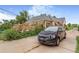 Charming home with a black car parked on the driveway and a wooden patio in a mature, landscaped yard at 2421 N York St, Denver, CO 80205