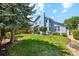 Large grassy backyard with lush green lawn, mature trees, and a view of the home's exterior at 5134 S Ouray Ct, Centennial, CO 80015