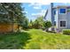 Expansive backyard featuring lush green lawn, mature trees, privacy fence, and covered patio area at 5134 S Ouray Ct, Centennial, CO 80015