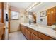 Bathroom with double sink, light-toned wallpaper, and wooden cabinets at 5134 S Ouray Ct, Centennial, CO 80015