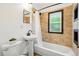 Well-lit bathroom featuring a pedestal sink, a white bathtub, and bright natural light at 9390 W 14Th Ave, Lakewood, CO 80215