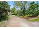 Long gravel driveway surrounded by lush trees, green grass, and landscaping at 9390 W 14Th Ave, Lakewood, CO 80215