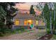 A single story house with a tan exterior, stone base, gravel driveway and a turquoise colored front door at 9390 W 14Th Ave, Lakewood, CO 80215