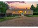 Cozy home with a stone base, tan stucco, a gravel driveway, colorful door and lush landscaping at sunset at 9390 W 14Th Ave, Lakewood, CO 80215