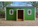 Green outbuilding features double doors, a simple gable roof, and white framed windows at 9390 W 14Th Ave, Lakewood, CO 80215