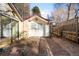 Rear view of white detached shed or office with double doors on a brick patio and surrounded by mature trees at 1602 Glen Bar Dr, Lakewood, CO 80215